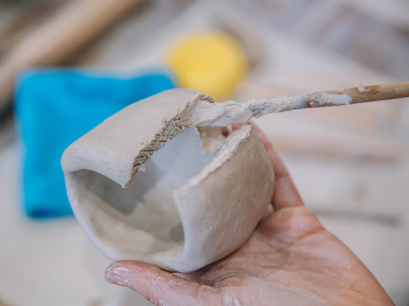 A paintbrush painting clay at a pottery class.